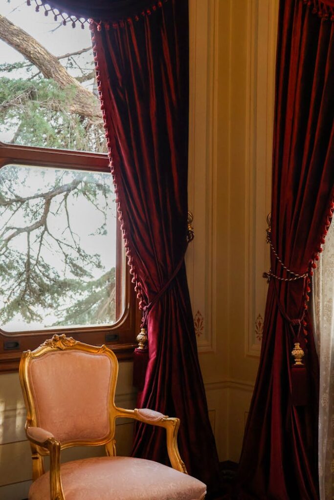 pexels-photo-35975117 A luxurious vintage room with red velvet curtains and a gold-framed chair.